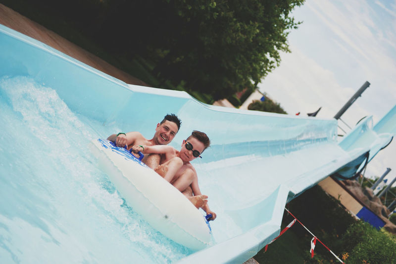 Portrait of happy man with son enjoying on water slide 