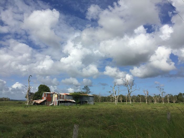 Barn on grassy field against cloudy sky
