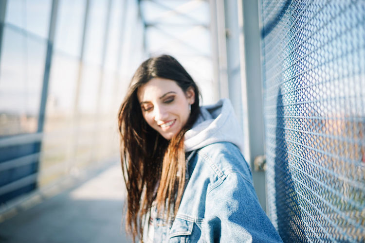 Portrait of smiling young woman leaning on fence