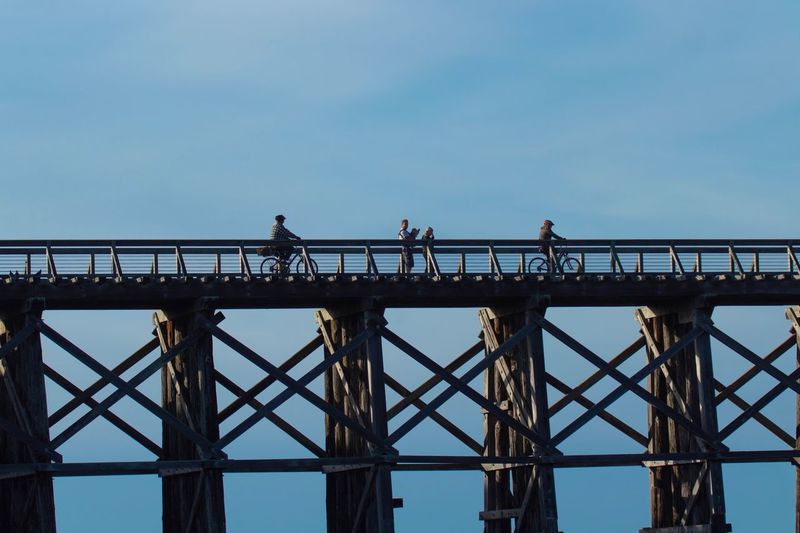 Low angle view of people on bridge against clear sky