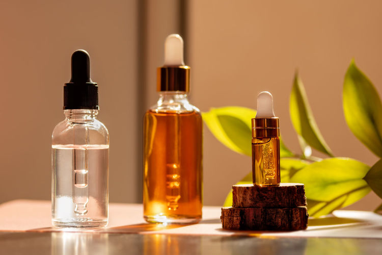 Cosmetic glass dropper bottles with serum, oil in sunlight. beauty composition on natural background