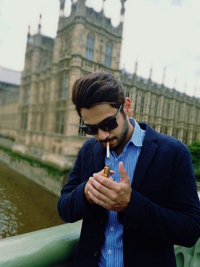Handsome man smoking on london bridge against historic building