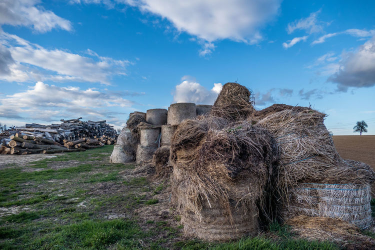 Stack of hay bales on field against sky
