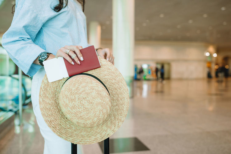 Midsection of woman holding hat with passport