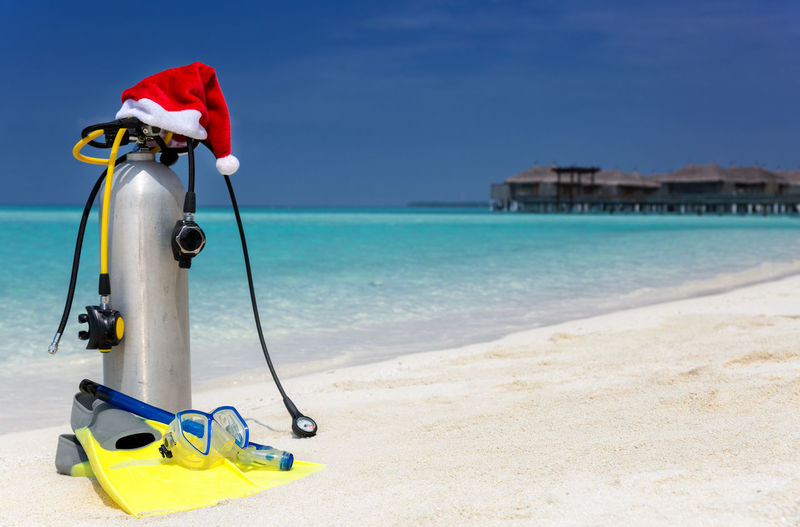 Santa hut on oxygen tank at beach against blue sky
