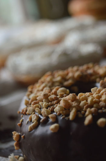Photograph of a donut covered in chocolate and sweet crunchy peanut pieces