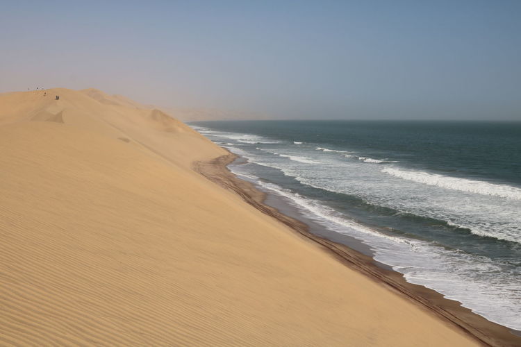Sand dune by sea against sky