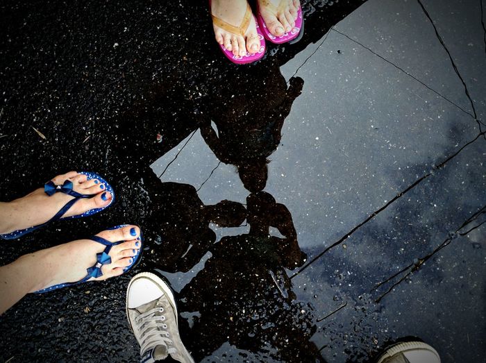 Low section of friends standing by puddle on street