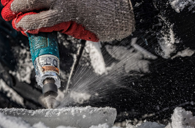 Cropped image of hand drilling on ice