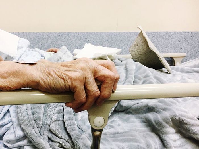 Hand of old man in hospital bed