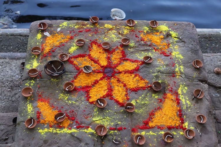 High angle view of powder paint with diyas by river