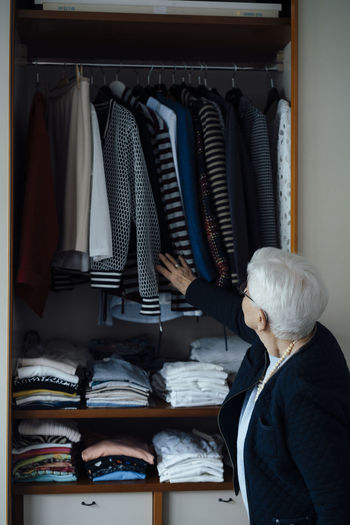 Senior woman choosing clothes in closet at home