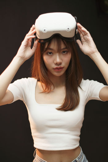 Young woman wearing hat standing against black background