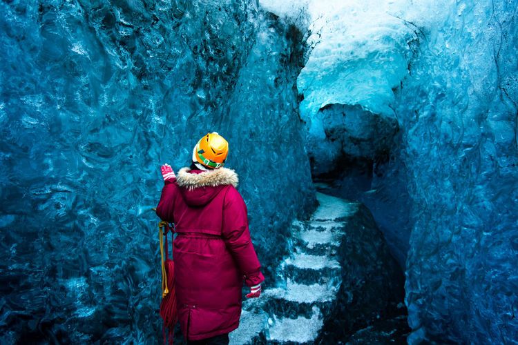 Rear view of woman standing at ice cave entrance