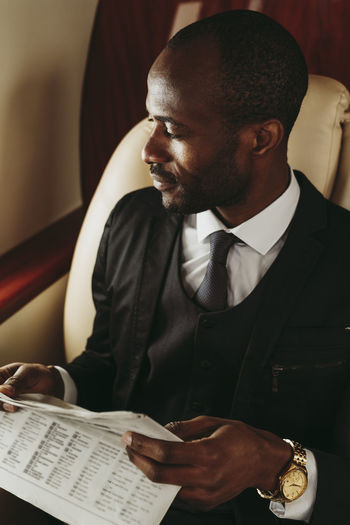 Businessman with newspaper looking away in private jet