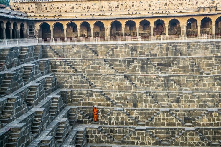 High angle view of woman standing on steps by wall at chand baori
