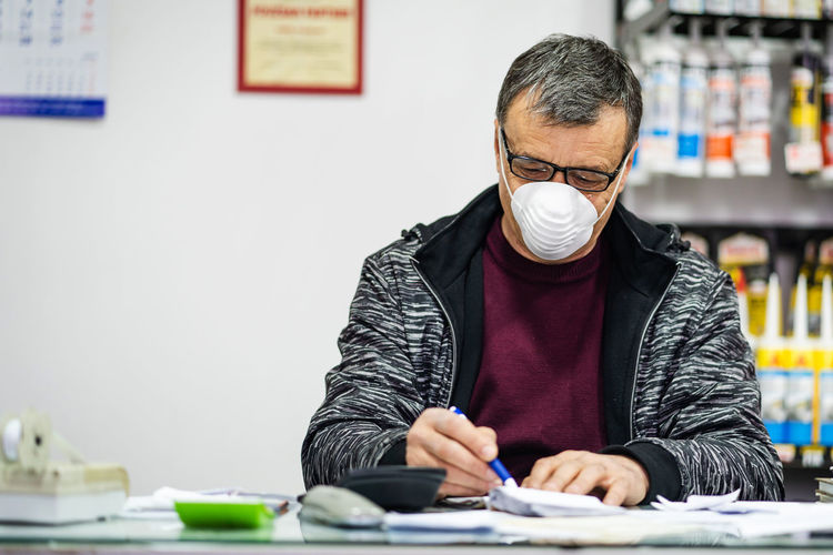 Man wearing mask sitting at counter in store