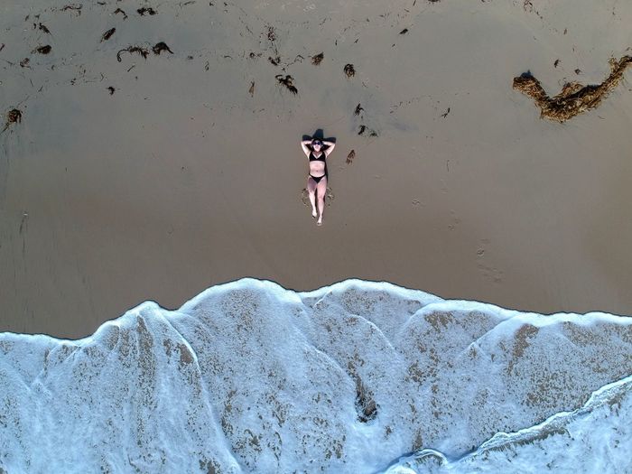 Aerial view of woman relaxing on sea shore at beach
