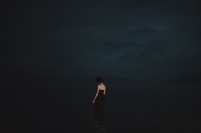 WOMAN STANDING ON BEACH AGAINST SEA AGAINST SKY