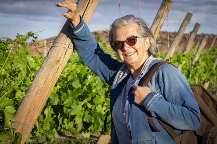 Portrait of smiling senior woman standing in vineyard