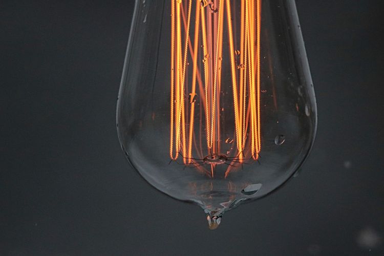 Close-up of water drops on illuminated light bulb at night