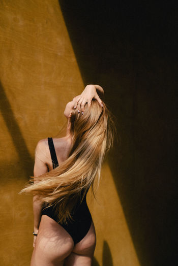 Rear view of woman dancing against wall