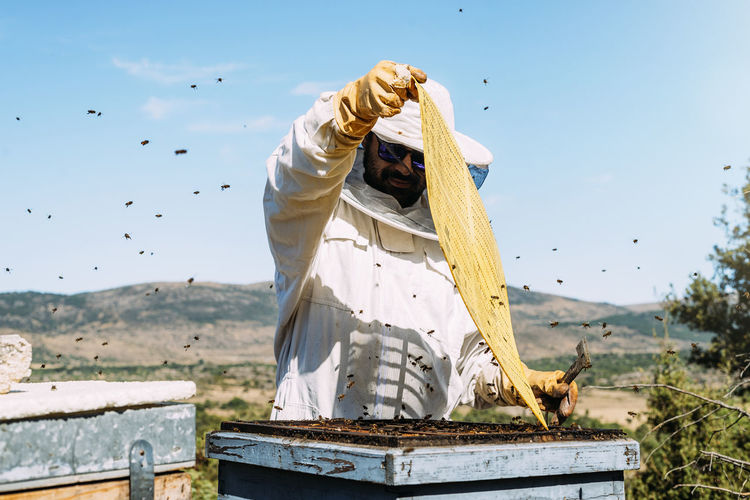 Beekeeper working against sky
