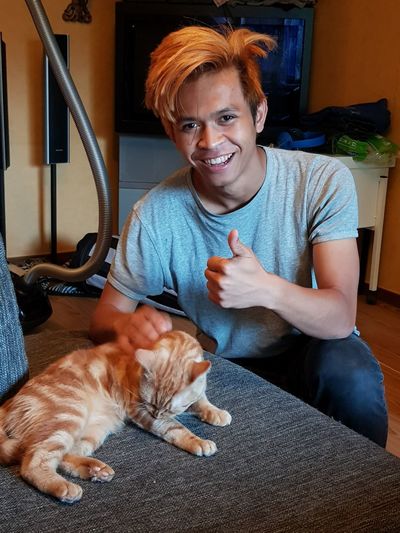 Portrait of smiling man with cat gesturing at home