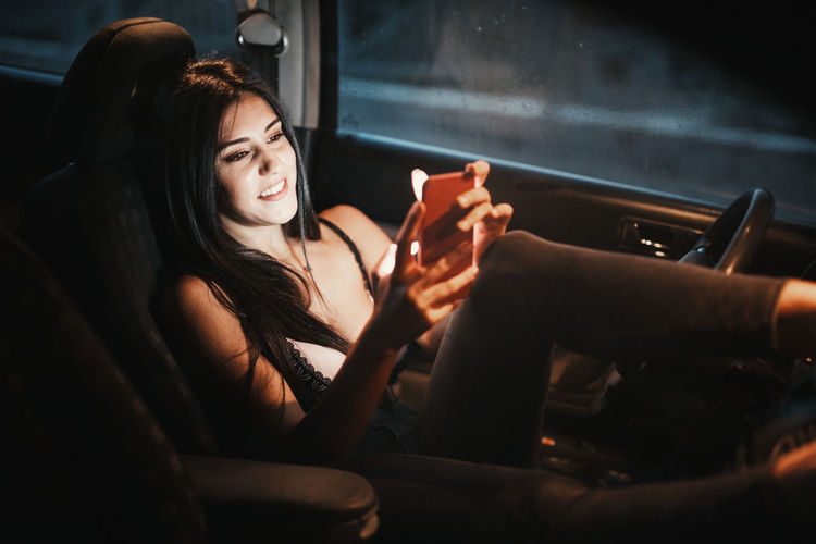 Young woman using smart phone while sitting in car