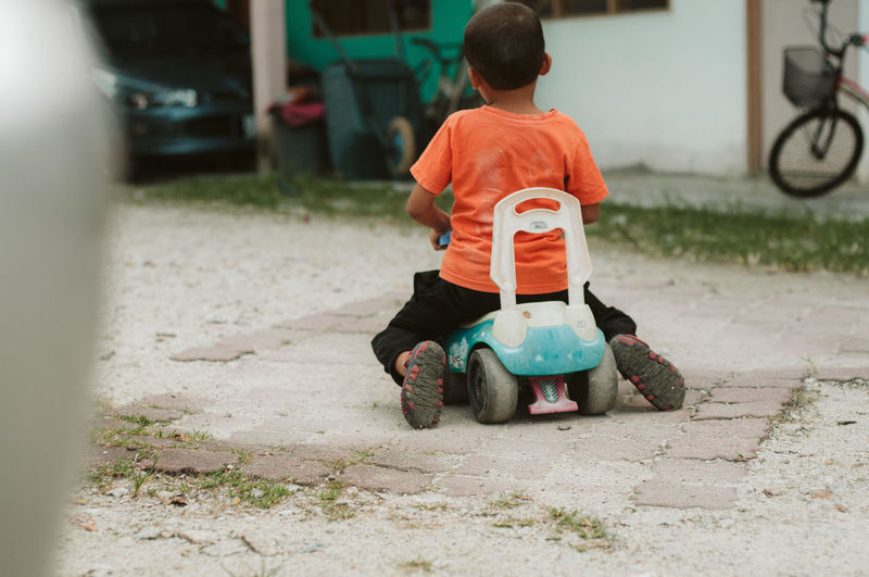Rear view of boy with toy car on street