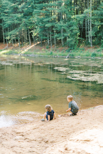 Two children exploring nature at a local pond in the woods