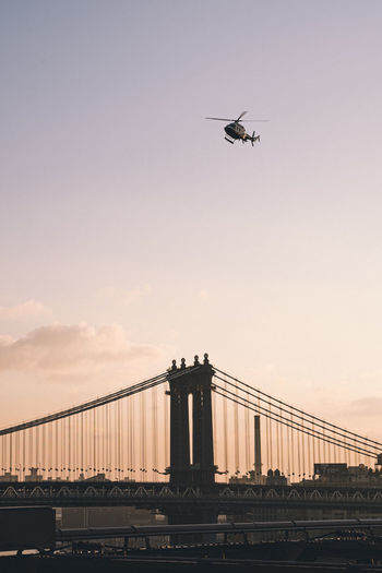 Low angle view of helicopter flying over manhattan bridge