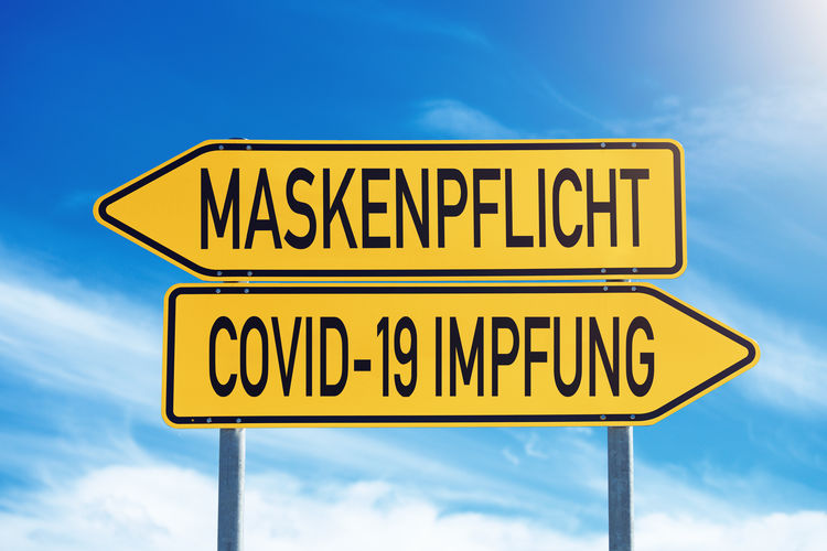 Mask obligation or covid-19 vaccination, traffic sign with the choice maskenpflicht impfung