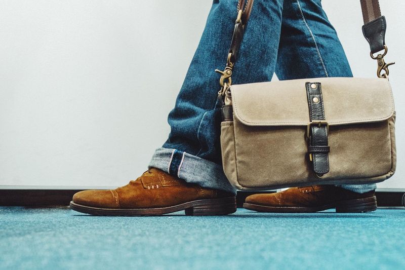 Low section of man with bag standing on floor