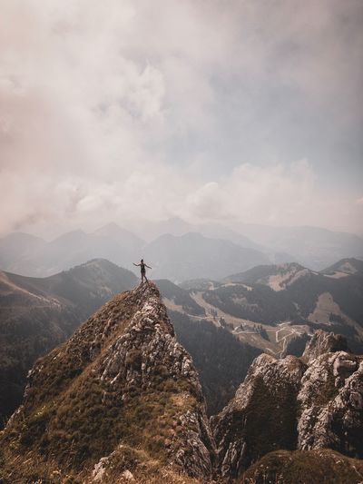 Woman standing on mountain peak against sky