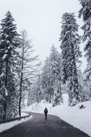 Rear view of man walking on snow covered road