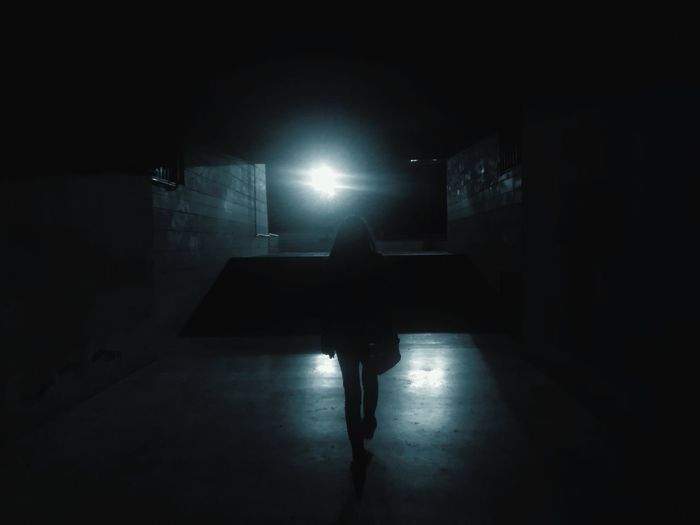 Rear view of silhouette man standing in illuminated building