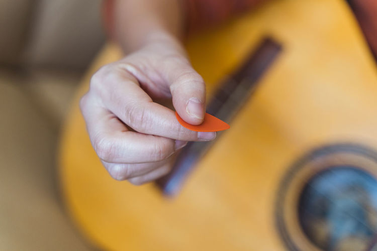 Cropped hand of woman playing guitar in home