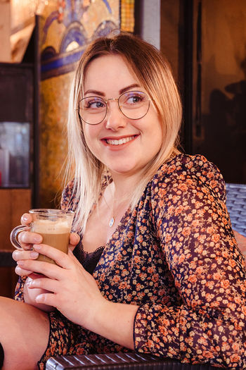 Smiling young woman holding coffee while sitting at home