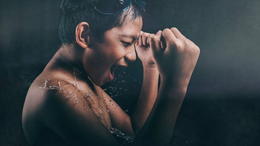 Close-up of shirtless boy with water