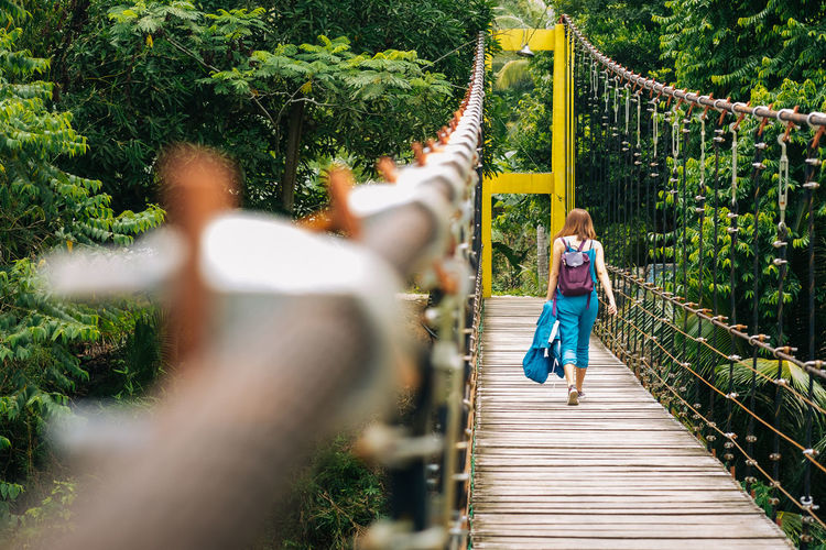 Rear view of woman on footbridge in park
