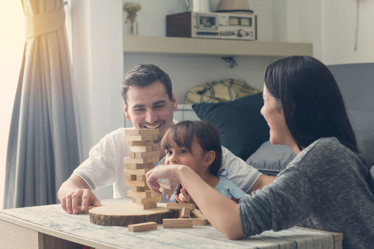 Happy family playing with wooden blocks on table at home