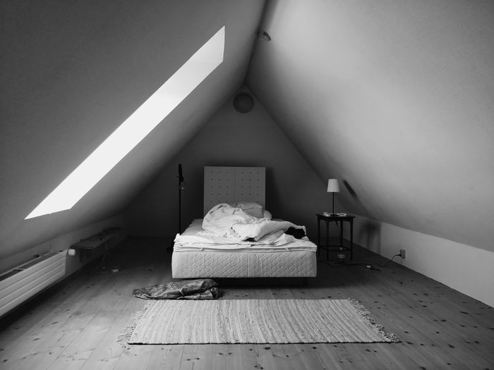 Empty minimalist attic bedroom with sunflooded window