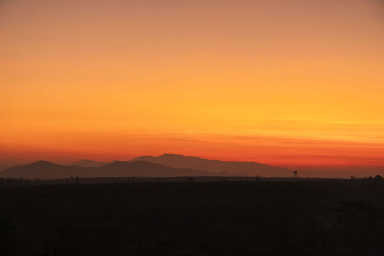 Scenic view of silhouette landscape against orange sky