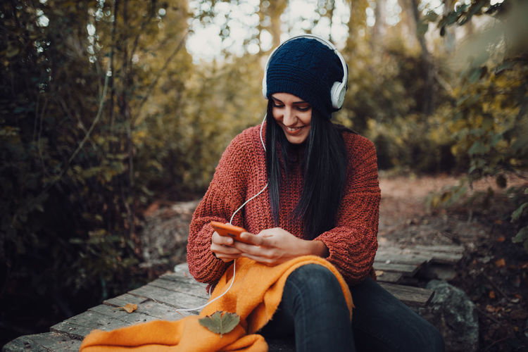 Beautiful young woman sitting on street during autumn