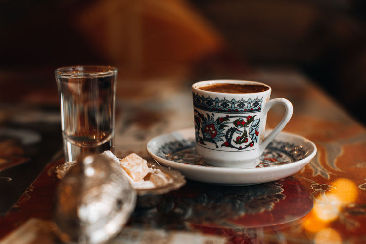 A cup of traditional black strong turkish coffee, sweets delight and a small glass of water. 