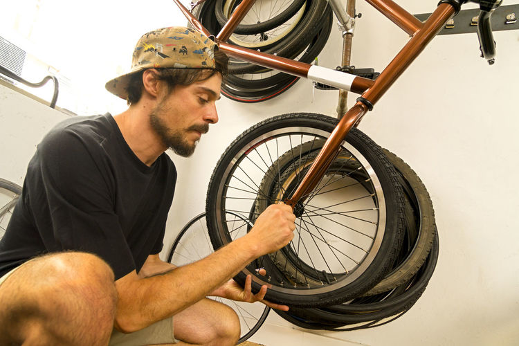 Side view of young man repairing bicycle tire in workshop