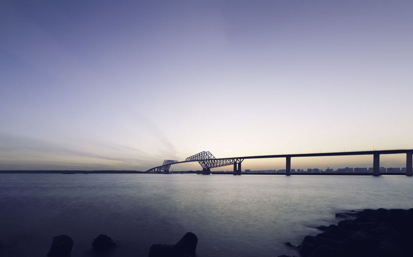 Bridge over calm sea against clear sky