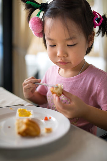 Close-up of cute girl eating food at table