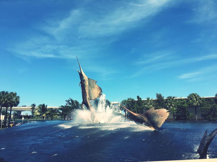 Swordfish statues in fountain against sky